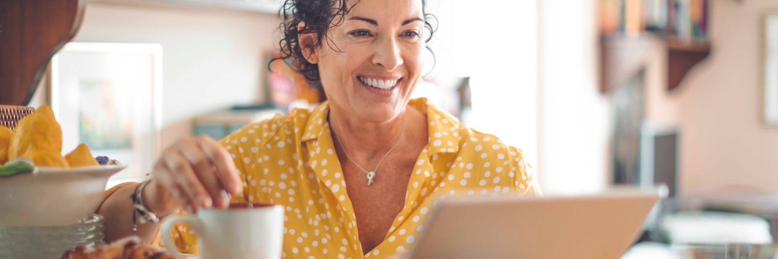 woman wearing a yellow shirt smiling looking at computer