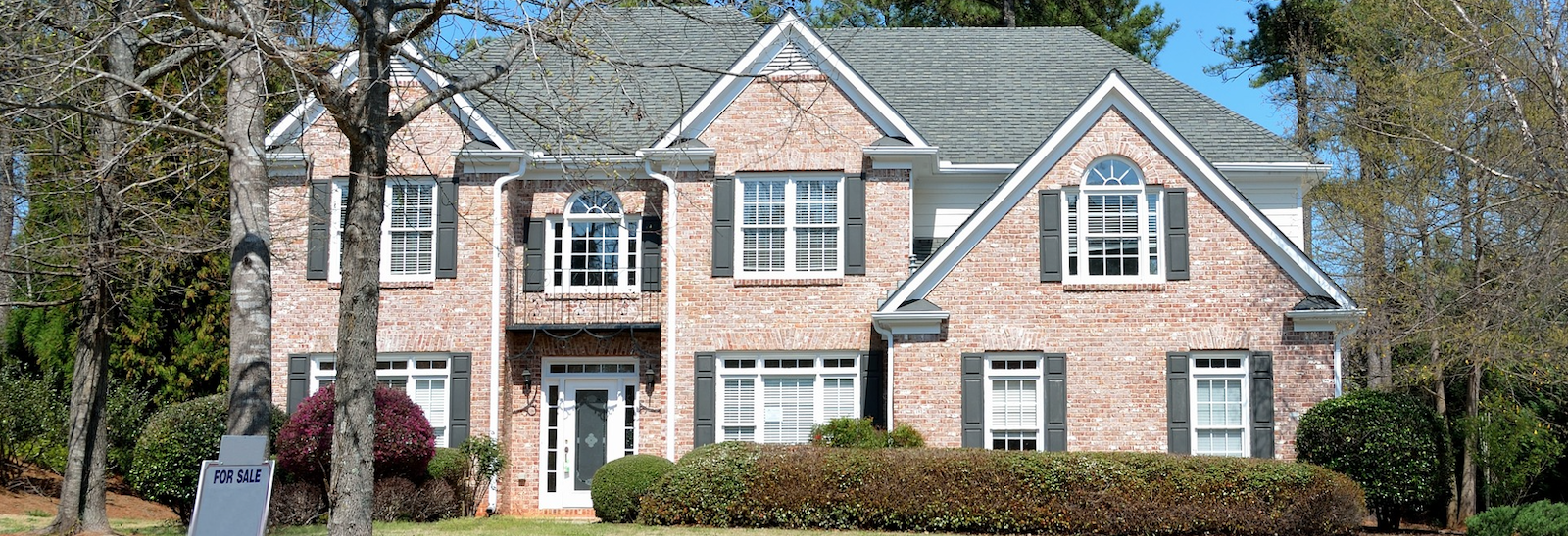 two-story home with for sale sign in front